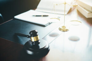 Justice and Law concept. Legal counsel presents to the client a signed contract with gavel and legal law or legal having team meeting at law firm in background